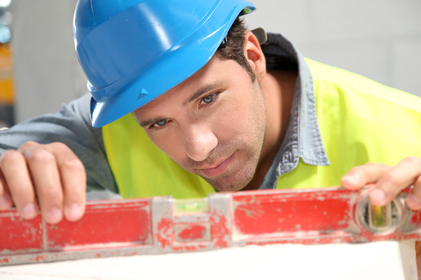 Worker using level on building site